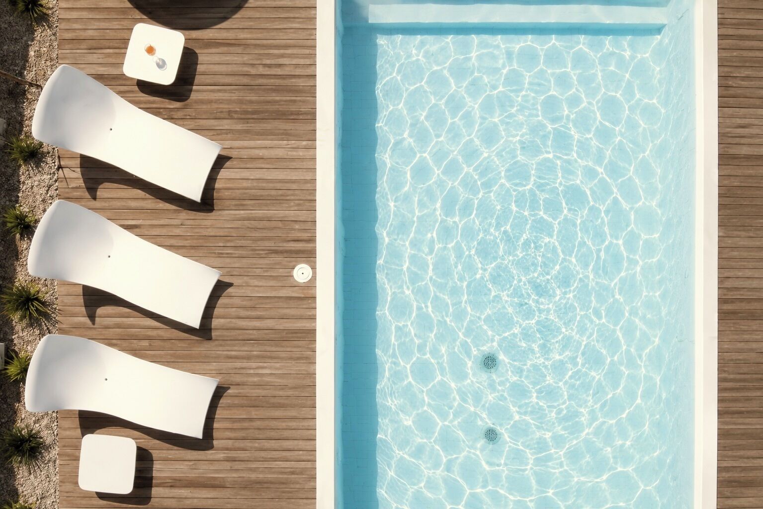 Ein rechteckiger Pool mit klarem Wasser und einer Holzterrasse.