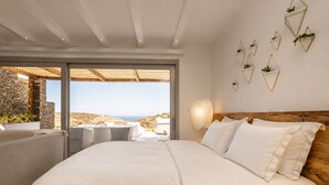 Ein Schlafzimmer mit einem großen Bett, Blick ins Freie und einer Steinwand.