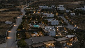 Ein Luftbild eines modernen Resorts mit Pool, mehreren Gebäuden und einer kurvenreichen Straße.