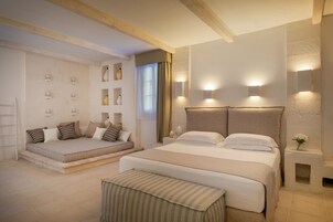 A modern bedroom with a large bed, a sofa bed, and a small table with a vase.