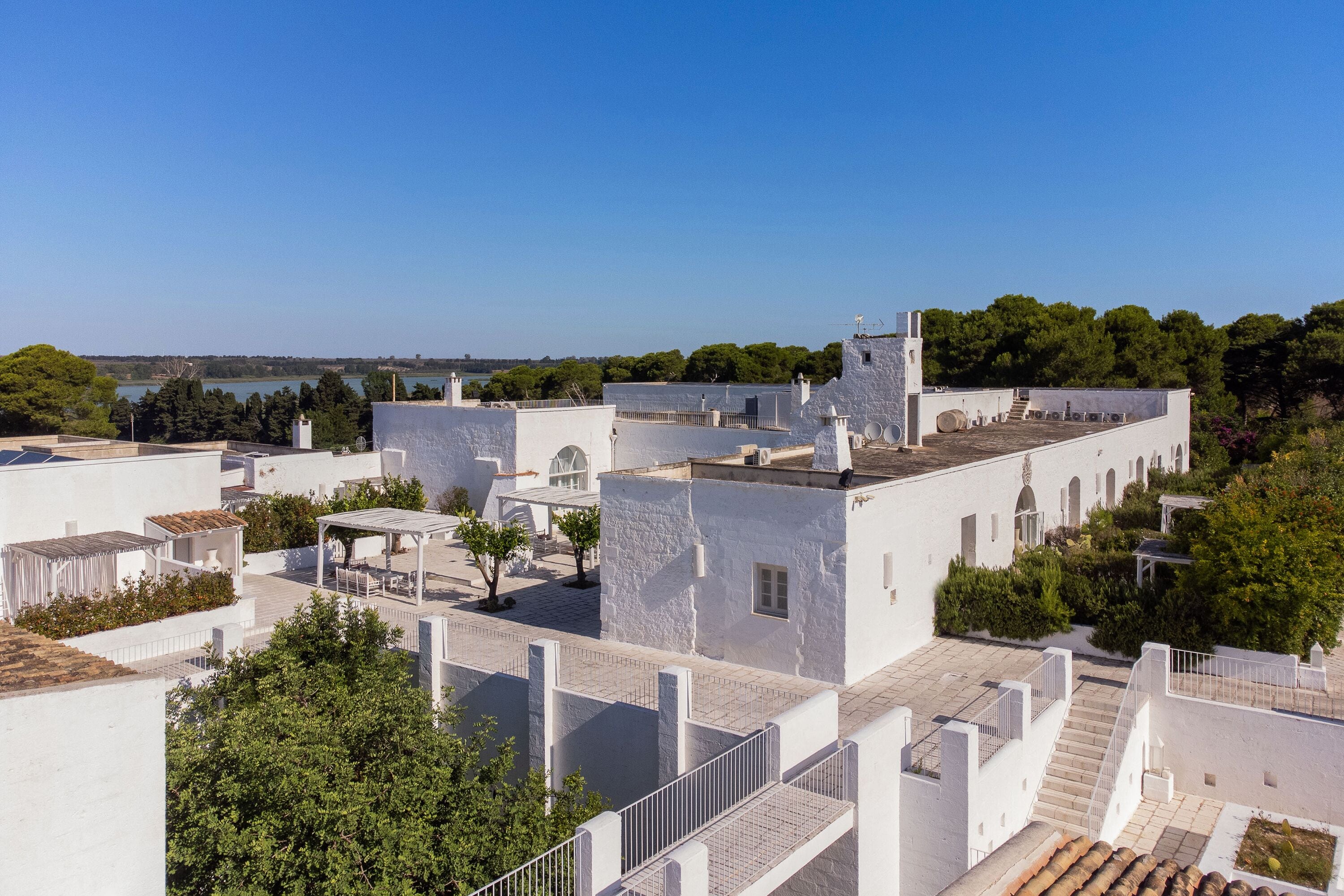 Ein weißes Gebäude mit Innenhof, Treppe und Blick auf das Meer.