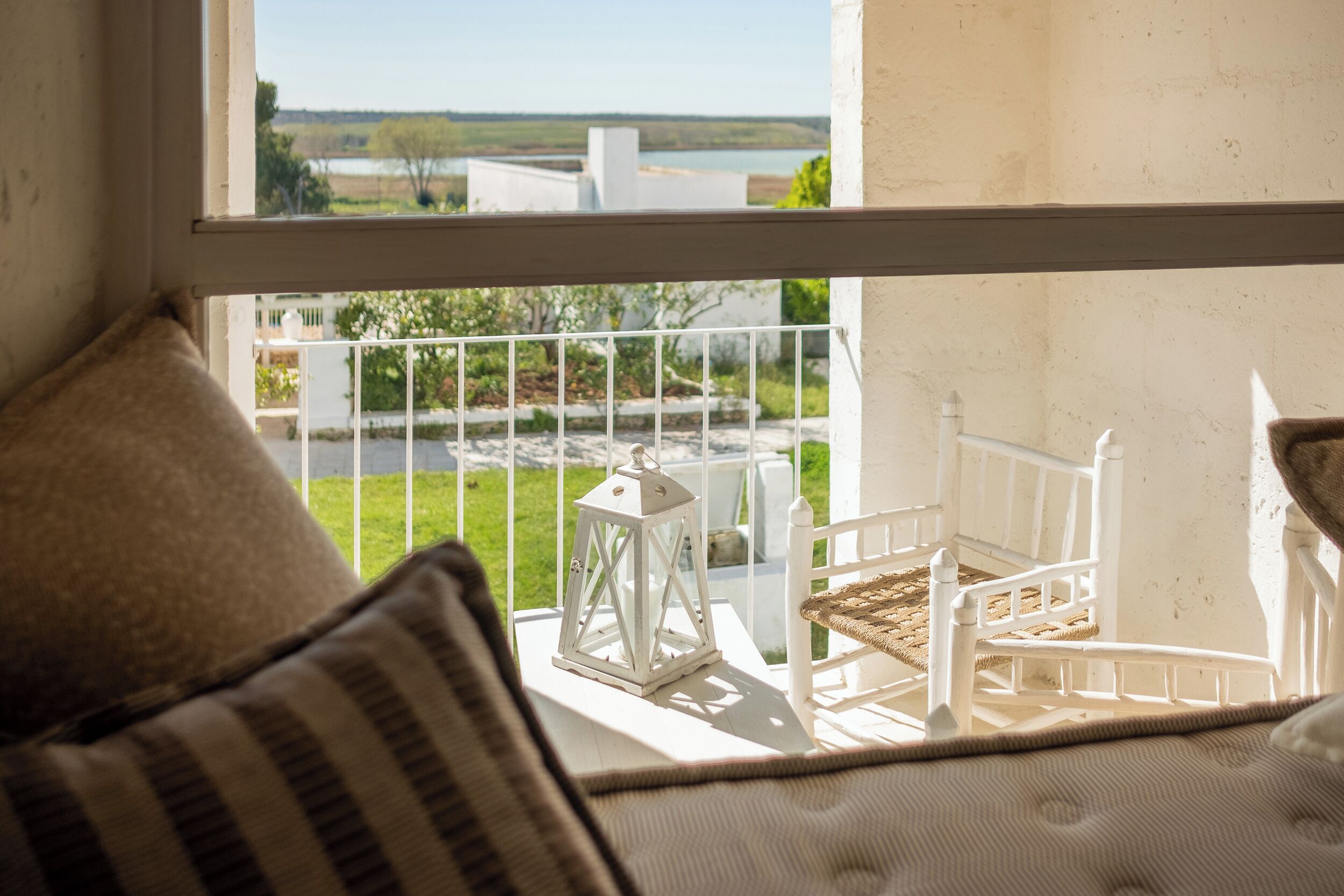 A balcony with a white railing, a white lantern, and a wicker chair.