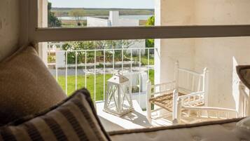 A balcony with a white railing, a white lantern, and a wicker chair.