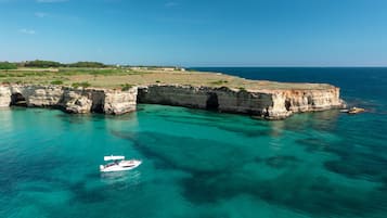A coastal landscape with cliffs and clear turquoise waters.