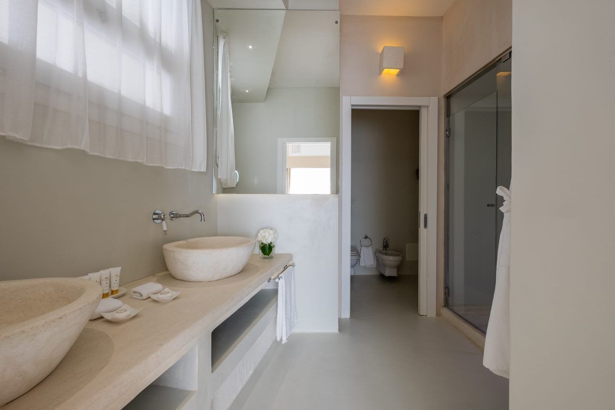Un baño moderno con un lavamanos grande color beige, un espejo y una cabina de ducha de vidrio.