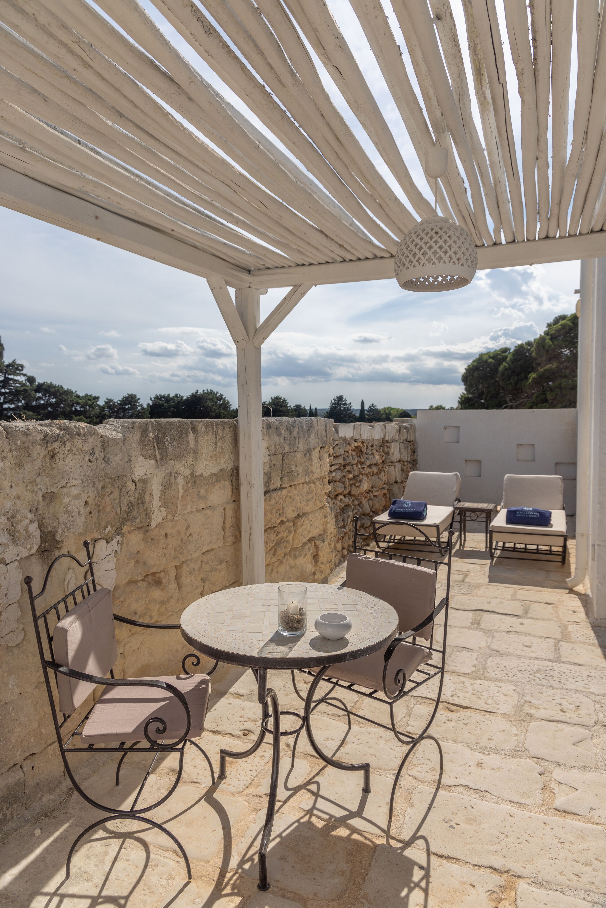Un espace extérieur abrité, avec une table et des chaises, des murs en pierre et une vue sur le ciel.