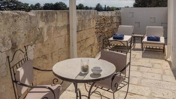Un espace extérieur abrité, avec une table et des chaises, des murs en pierre et une vue sur le ciel.