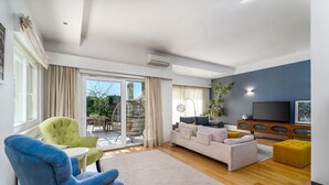 Un salon moderne comprenant un canapé, des fauteuils, un téléviseur et un coin repas avec une table et des chaises.