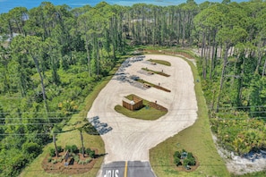 An aerial view of a parking lot with a building, surrounded by dense forest.