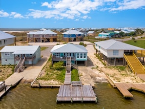 Uma área residencial costeira com casas sobre palafitas, ligadas por passarelas.