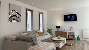 Un saló modern amb un sofà, una taula de centre, una televisió i un moble d'armari.