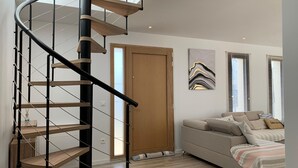 Un interior modern amb una escala espiraltra, un sofà i una porta.