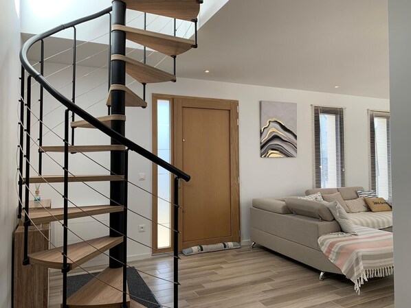 Et moderne interiør med en spiraltrappe, en sofa og en dør.
