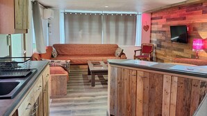 A modern kitchen with wooden cabinets, a central island, and a dining area with a sofa and chairs. - The Terre de feu mobile home (Châteauneuf-sur-Isère)