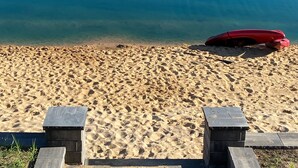 A sandy beach with a clear view of a house across the water.
