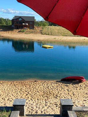 En sandstrand med fri sikt över ett hus på andra sidan vattnet.