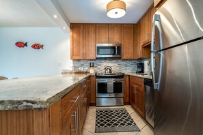 Enjoy cooking in this kitchen with a refrigerator, microwave, and oven, complemented by cabinets and a countertop.