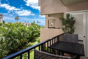 Enjoy a serene view of the lush garden and palm trees from this hotel's balcony, complete with a table and comfortable seating.
