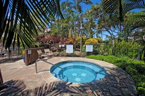 Une piscine circulaire bordée de carreaux, entourée de palmiers et de différentes espèces de plantes.