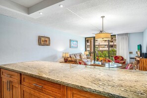 Enjoy meals in the spacious kitchen area with a large countertop and dining table, surrounded by comfortable seating and a beautiful view.