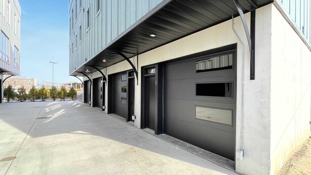 Een modern gebouw met een overdekte doorgang en garagedeuren.