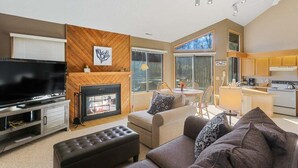 A modern living room with a fireplace, a television, and a dining area. - Abbey Springs Condo with Golf Cart Pools Private Beach and Waterfront Deck (Fontana)