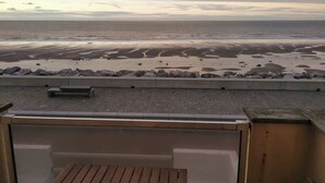 A beach view from a balcony with a wooden table and benches. - Gite de la Digue **** Wissant Cote d'Opale (Wissant)