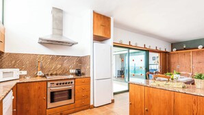 Een moderne keuken met houten kastjes, een inbouwoven, een magnetron en een roestvrijstalen afzuigkap.