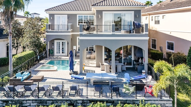Ein zweistöckiges Haus mit Swimmingpool, Außenbereich zum Sitzen und einer überdachten Terrasse.