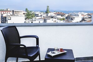 A black chair and a small table with a tray of food and drinks on a balcony overlooking a cityscape. - Emin Palace (Istanbul)