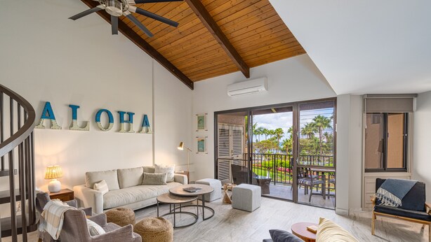 A spacious living area with a wooden ceiling, a large window offering a view of the outdoors, and a staircase leading to another level.