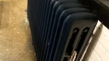 Diversos porta-bagagens azuis alinhados contra uma parede.