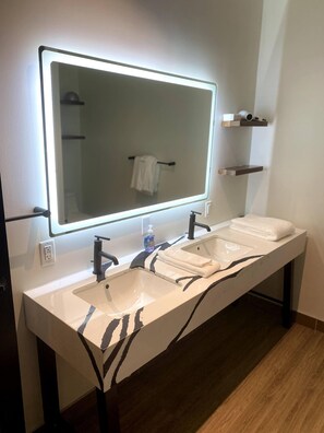 A modern bathroom with a long vanity, two sinks, a large mirror, and a towel rack. - 424-Apt 304 (Pittsburgh)