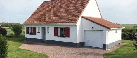 A single-story house with a red-tiled roof, white exterior walls, and a garage.