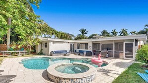 A backyard with a swimming pool, a hot tub, and outdoor seating.