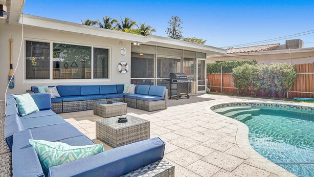 A backyard with a pool, outdoor seating, and a barbecue area.