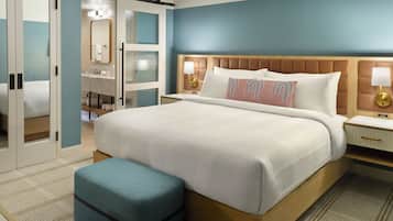 A hotel room with a large bed, a bedside table with a lamp, a wardrobe, and a bathroom visible through an open door.