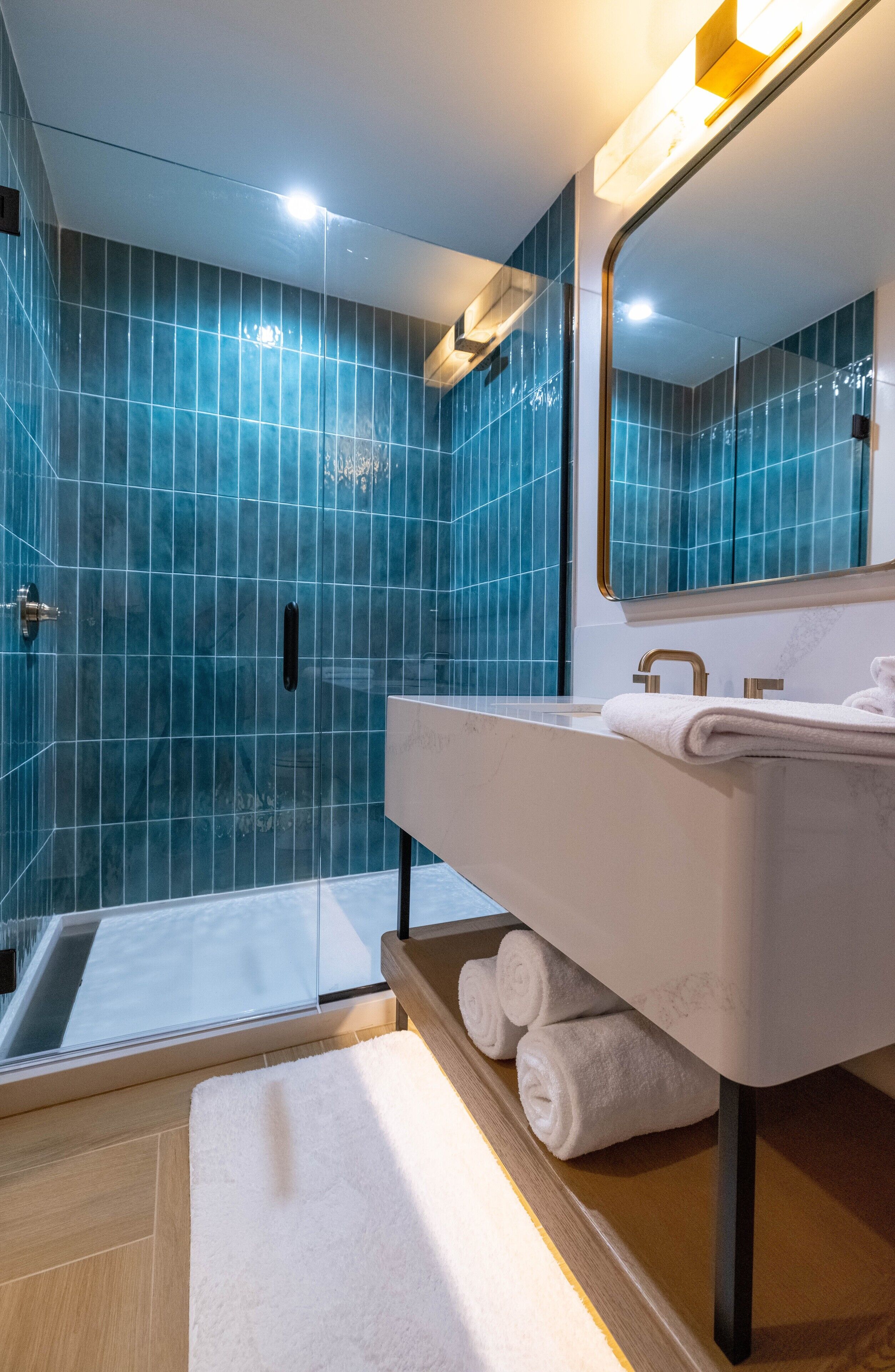 A modern bathroom with a glass shower enclosure, a vanity with a mirror, and a white towel on the counter.