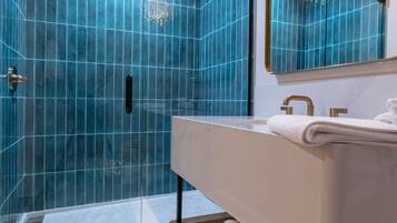 A modern bathroom with a glass shower enclosure, a vanity with a mirror, and a white towel on the counter.