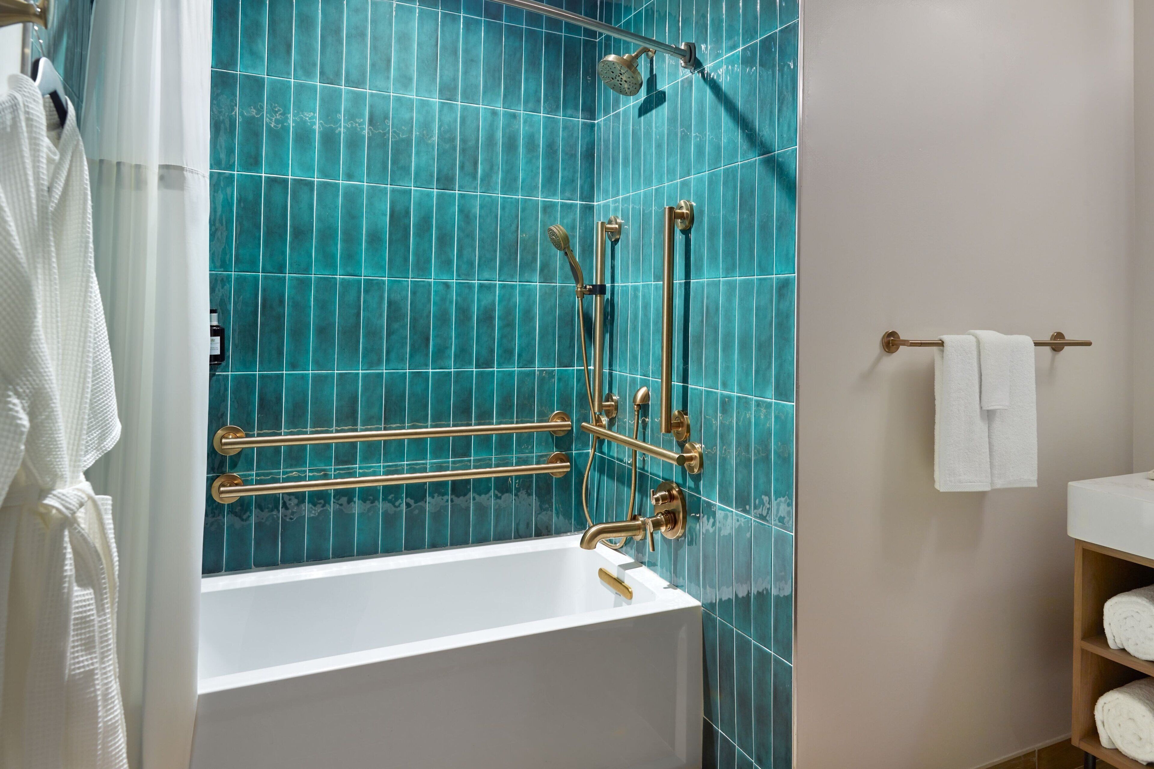 Une salle de bain avec une baignoire blanche, des murs recouverts de carreaux bleus et des accessoires dorés.