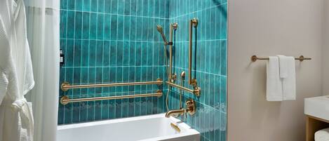 Un baño con una bañera blanca, paredes con azulejos azules y accesorios dorados.