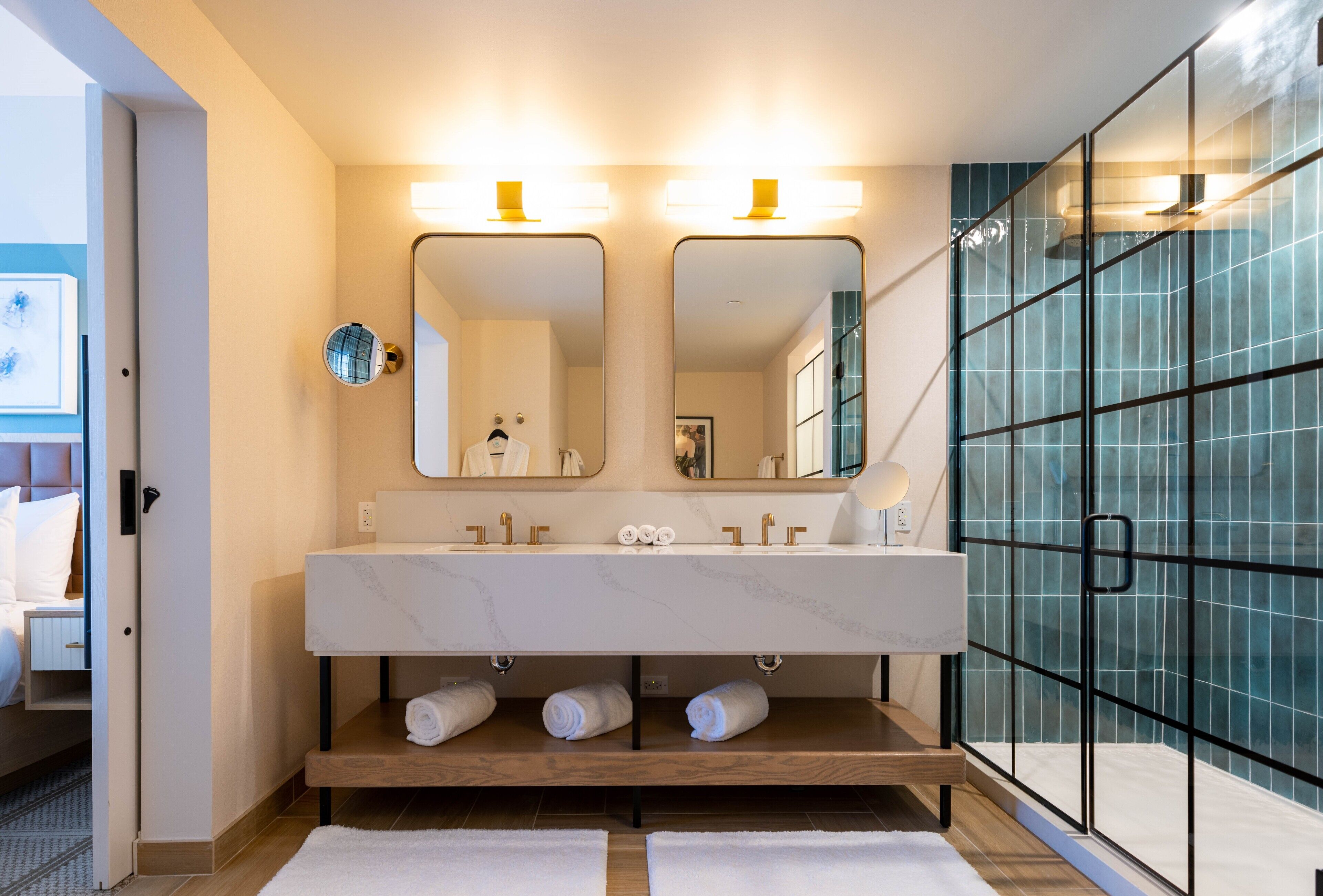 Une salle de bain moderne avec un meuble-lavabo en marbre, deux miroirs et une cabine de douche en verre.