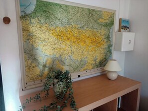 A large map on a wall, a small lamp on a wooden table, and a book titled "Les Pirenées".