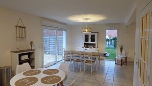 A dining area with a table and chairs, a kitchen area with cabinets, and a view of the backyard through a sliding door.