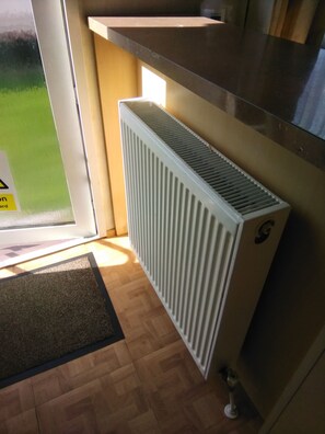 A room with a radiator, a doormat, and a wooden floor. - Inviting 3 Bedrooms Caravan gas Central Heating (Rye)