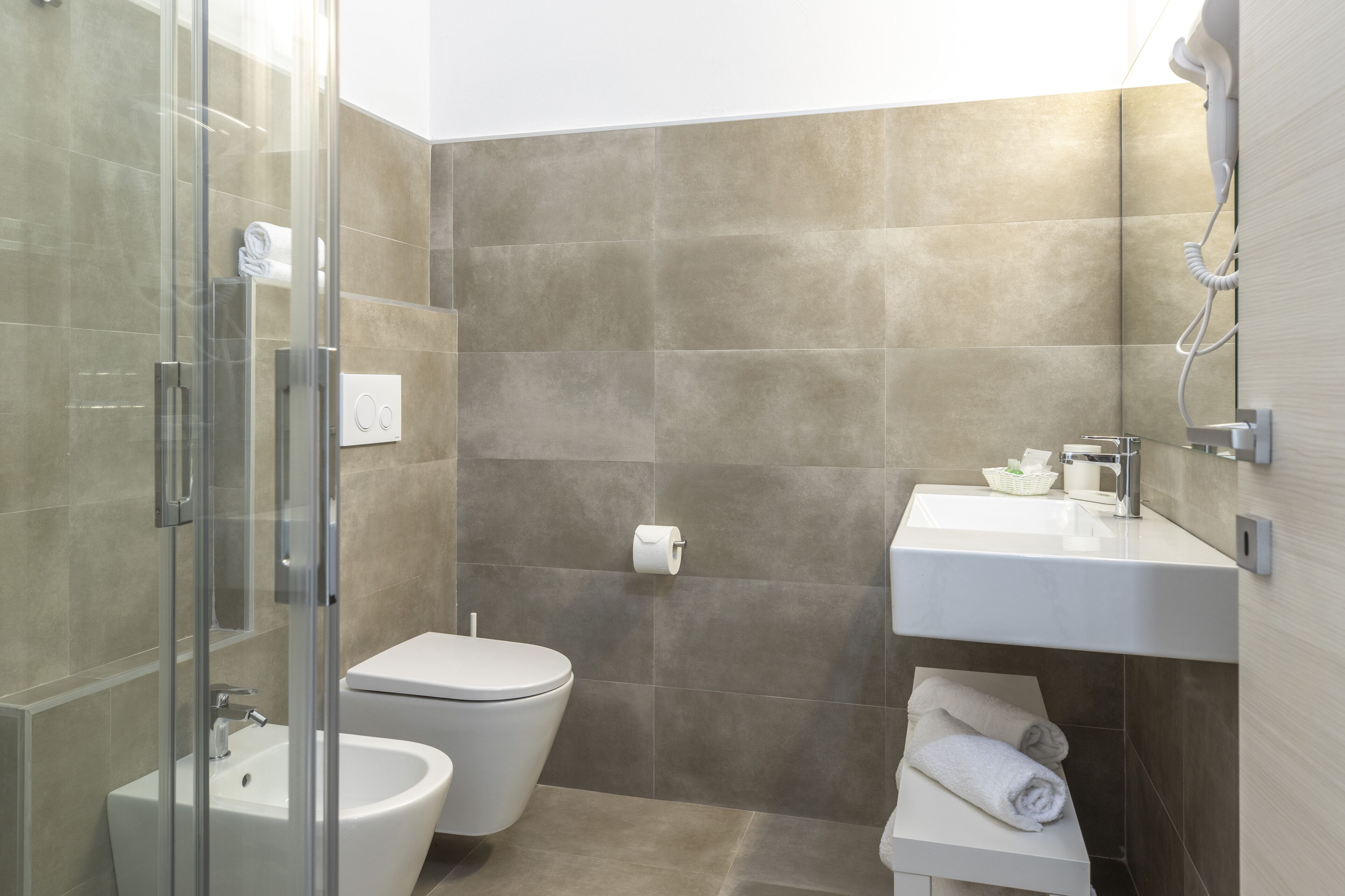 A modern bathroom with a glass shower enclosure, a white toilet, a sink, and a towel rack.