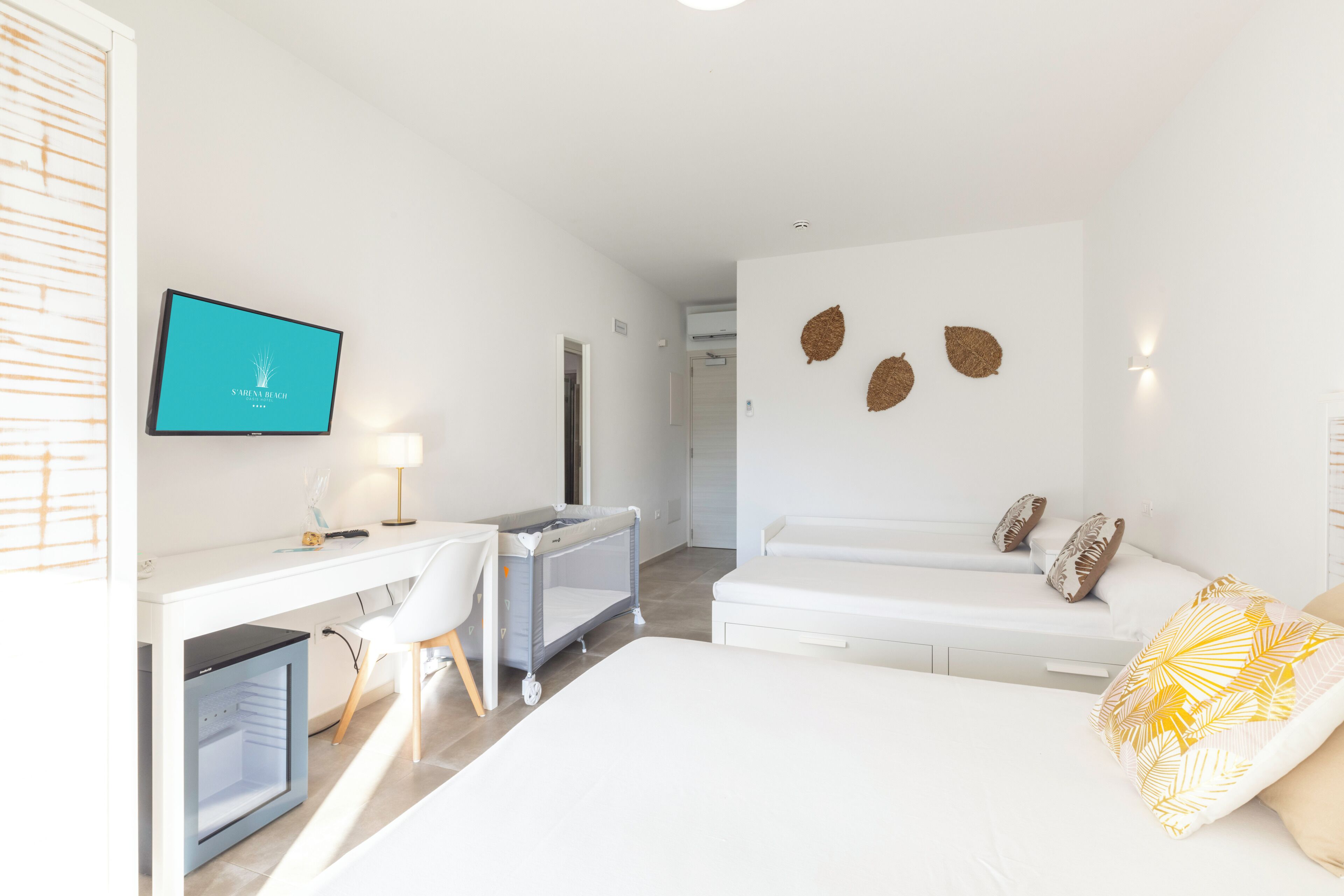 Una habitación de hotel con una cama, un escritorio, una silla, un televisor y una cuna.