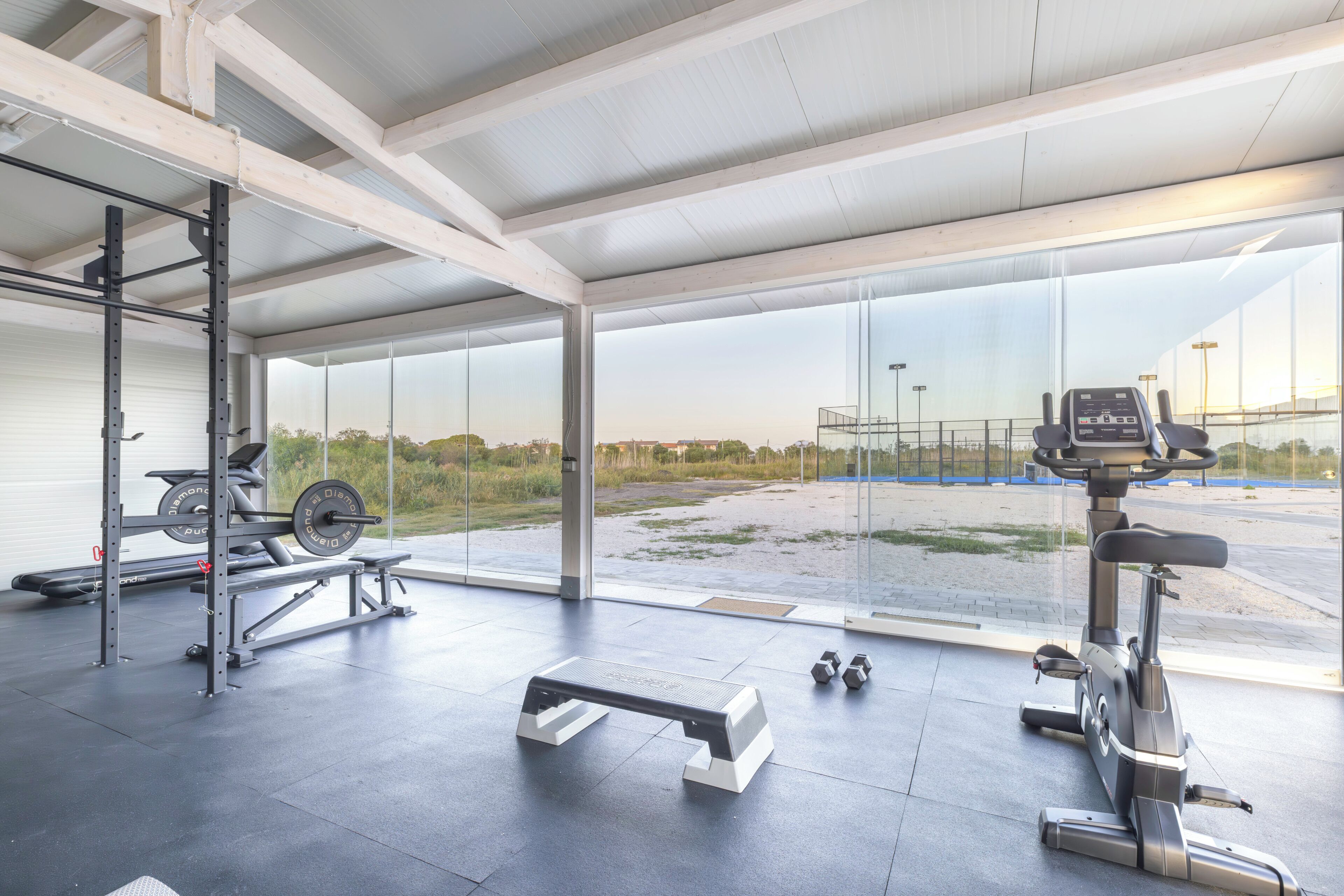 Une salle de sport équipée de matériel de musculation, d’une plateforme pour les exercices d’aérobic et d’un vélo d’exercice.