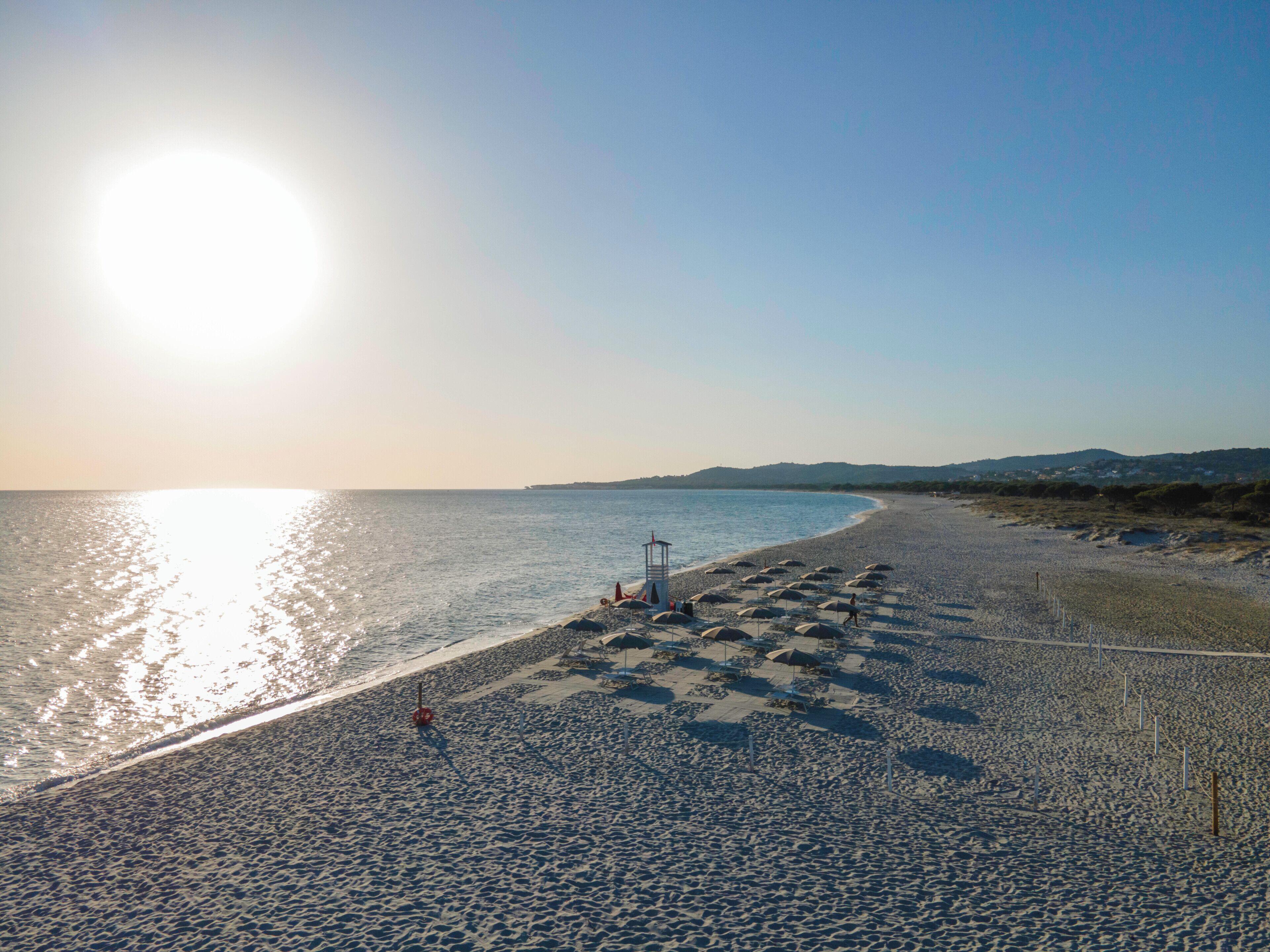 A beach with umbrellas and a lifeguard tower.