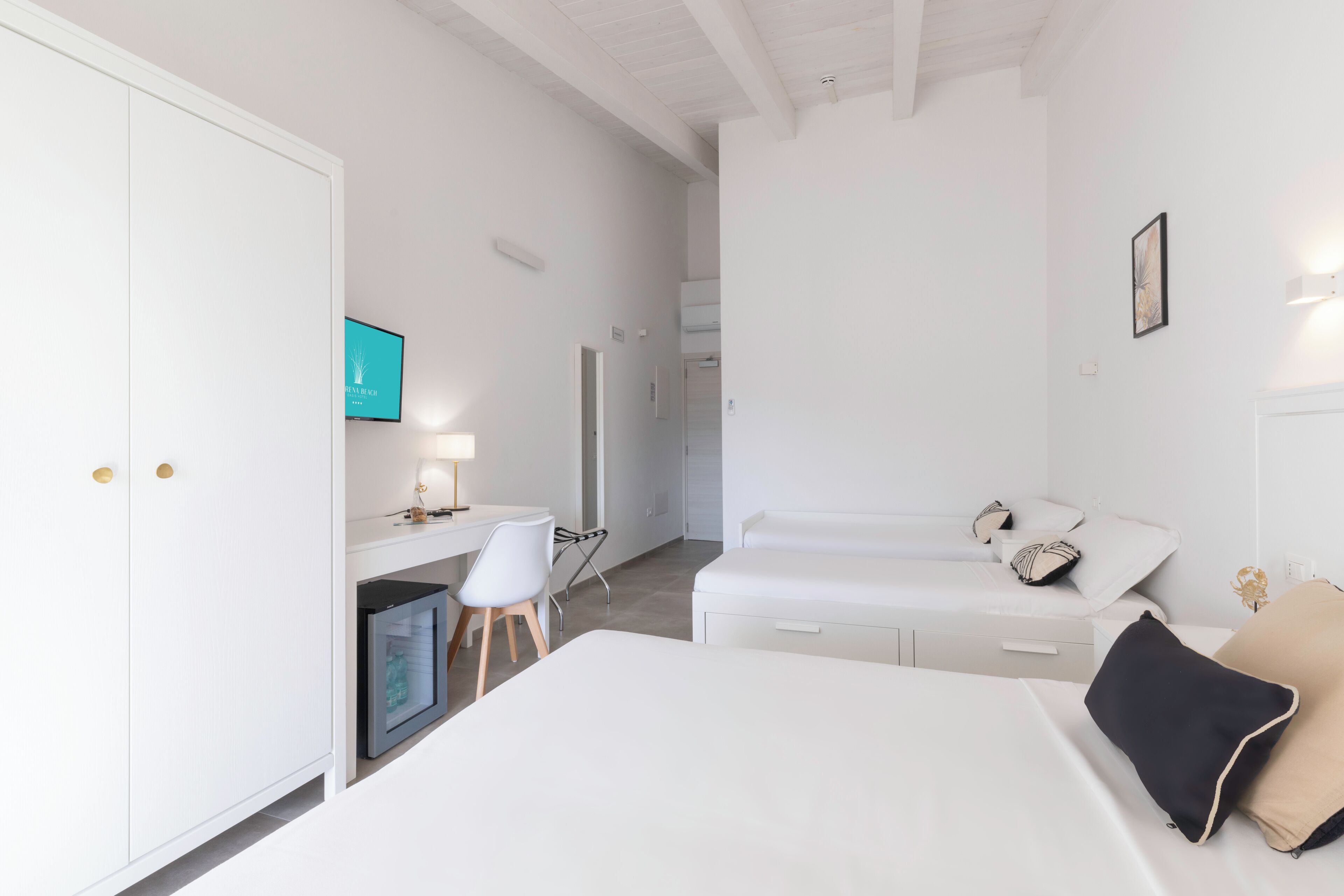 Una habitación de hotel moderna con cama, mesita de noche, escritorio, silla y armario.